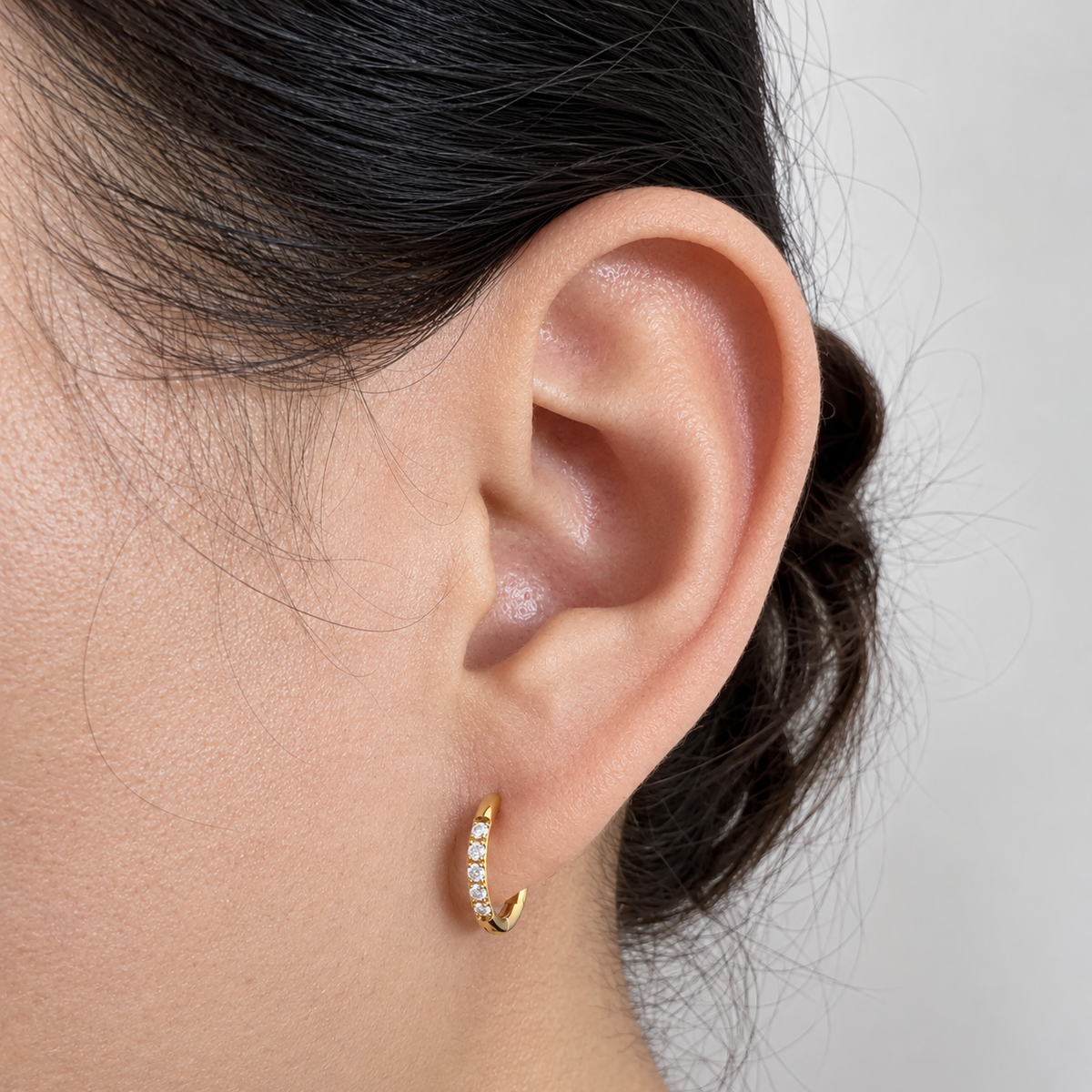 Close-up of Halo 10mm gold hoop earring worn on an earlobe