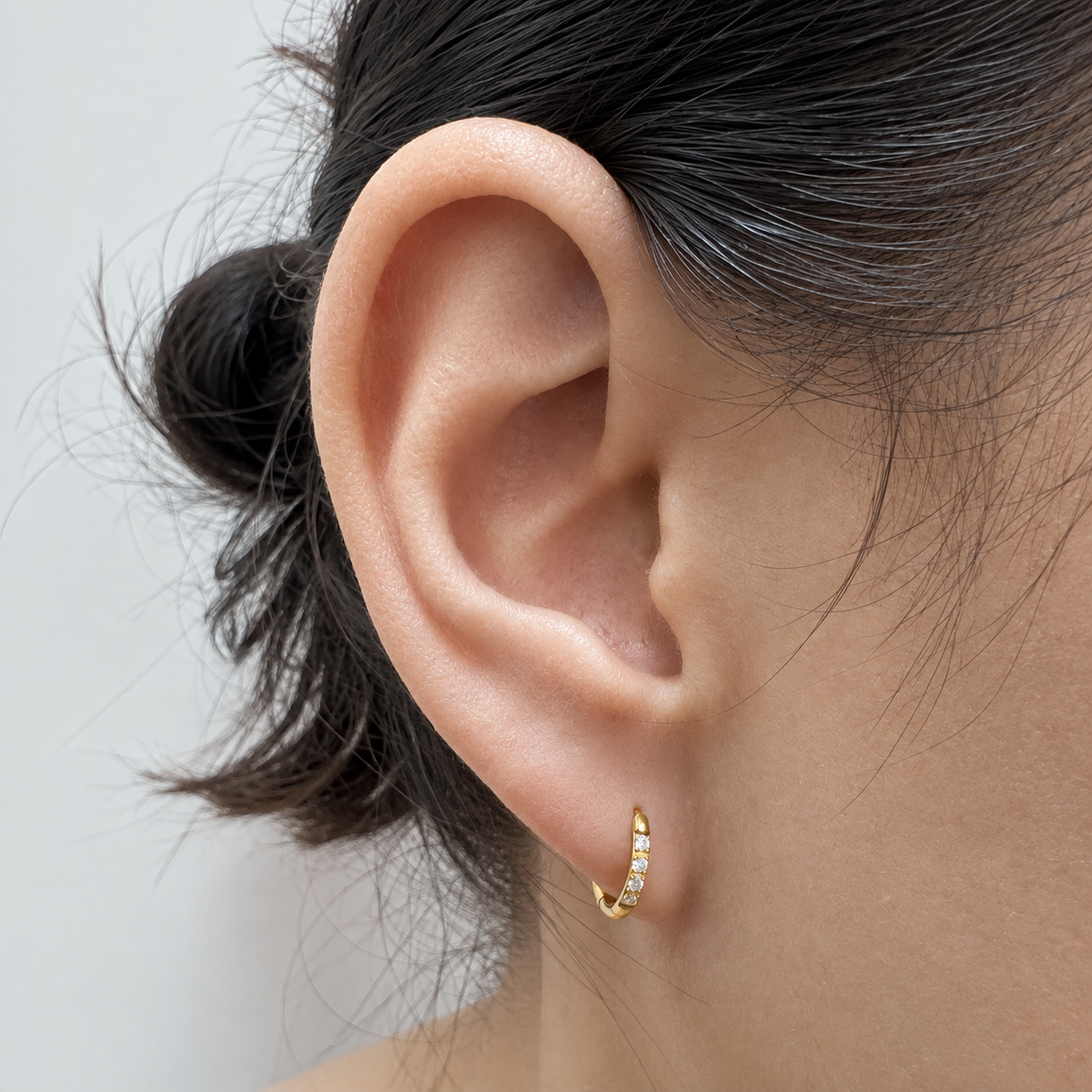 Close-up of Halo 8mm gold hoop earring worn on an earlobe