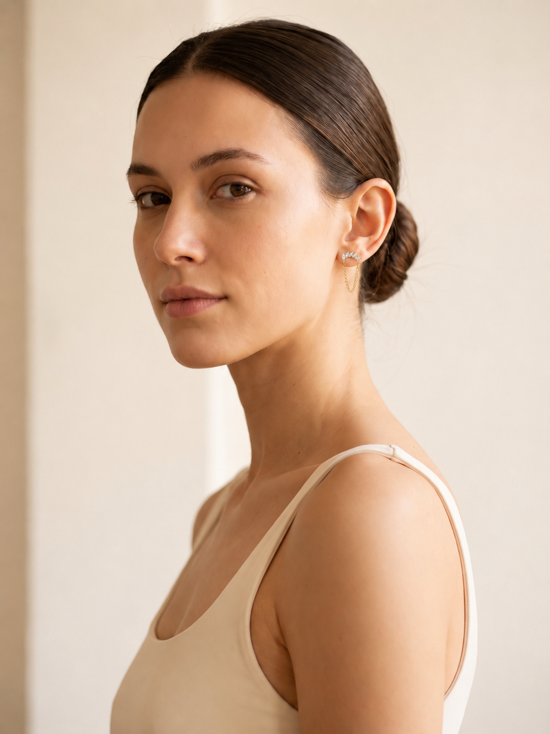 Woman wearing Lyra gold chain flat-back earrings on her earlobe